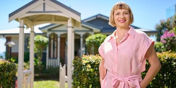 Woman in a pink dress standing in front of a house