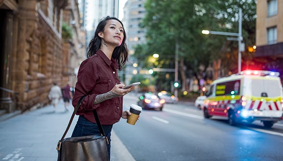 Woman standing on a street with ambulance in the background