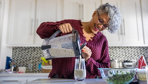 Lady pouring a smoothie into a glass