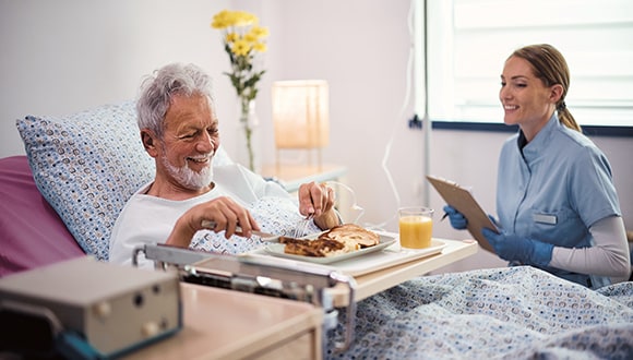 Man sitting in his hospital bed with a nurse