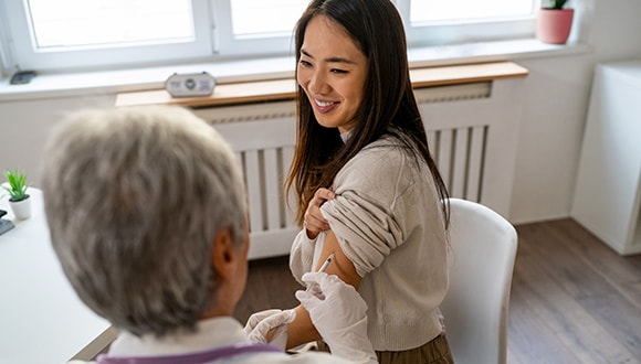 Lady getting a vaccination by the nurse using her extras cover