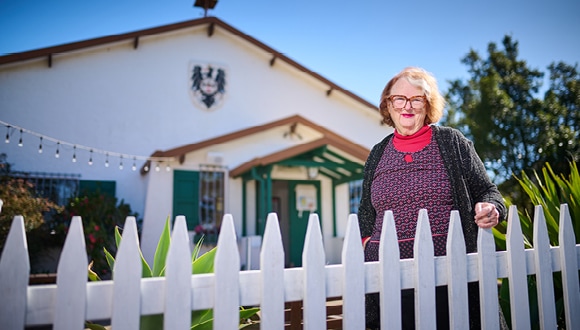 Jenny standing by a white fence