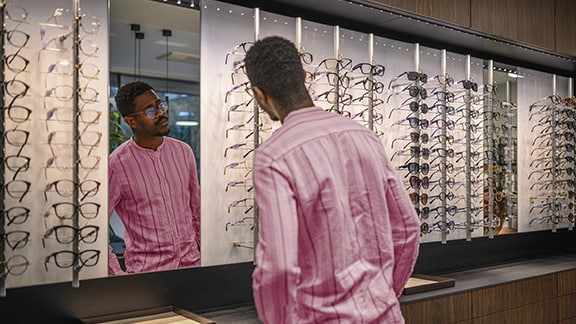 A man is trying on glasses at an optical store