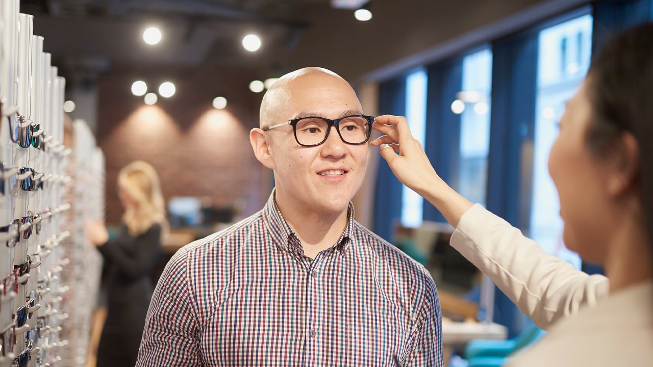 A man tries a new pair of eye glasses in a glasses store.