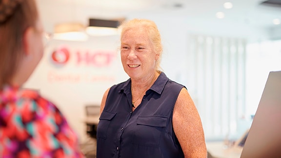 An old woman talking to another woman in front of a HCF health insurance logo.