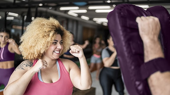 A woman boxing at a gym with her trainer